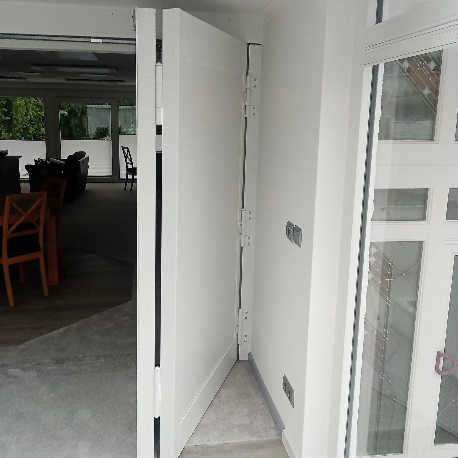 Offene Falt-Schiebetür in weißem Wohnraum mit Blick auf Küche und Esstisch