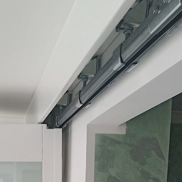 Oberlaufschiene für Schiebetür an weißer Decke mit grünem Wandbelag