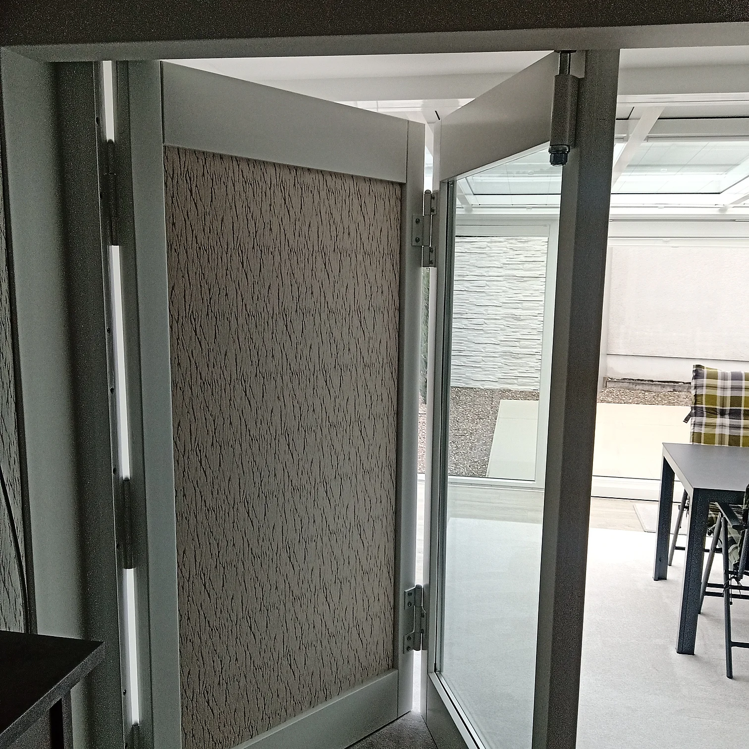 Offene Falt-Schiebetür mit strukturierter Tapete und Blick auf Terrasse